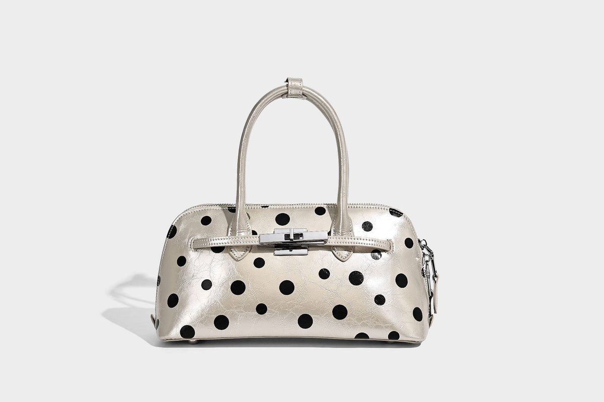Glossy structured polka-dot satchel bag with dual top handles, silver turn-lock hardware, and detachable shoulder strap