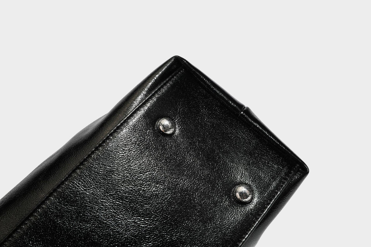 Glänzende schwarze, weich fallende Schultertasche mit gerafftem Abschluss, zwei langen Trageriemen, silberfarbenen Beschlägen und abnehmbarem Umhängeriemen