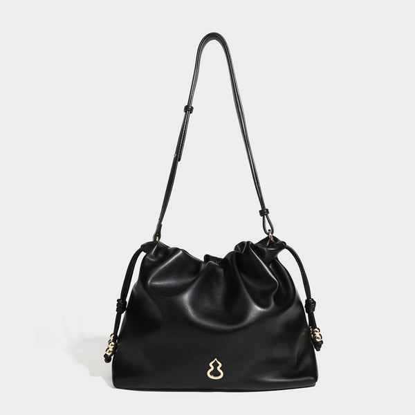Slouchy ruched drawstring shoulder bag in smooth leather-look finish with gold-tone emblem and slim adjustable strap, detail