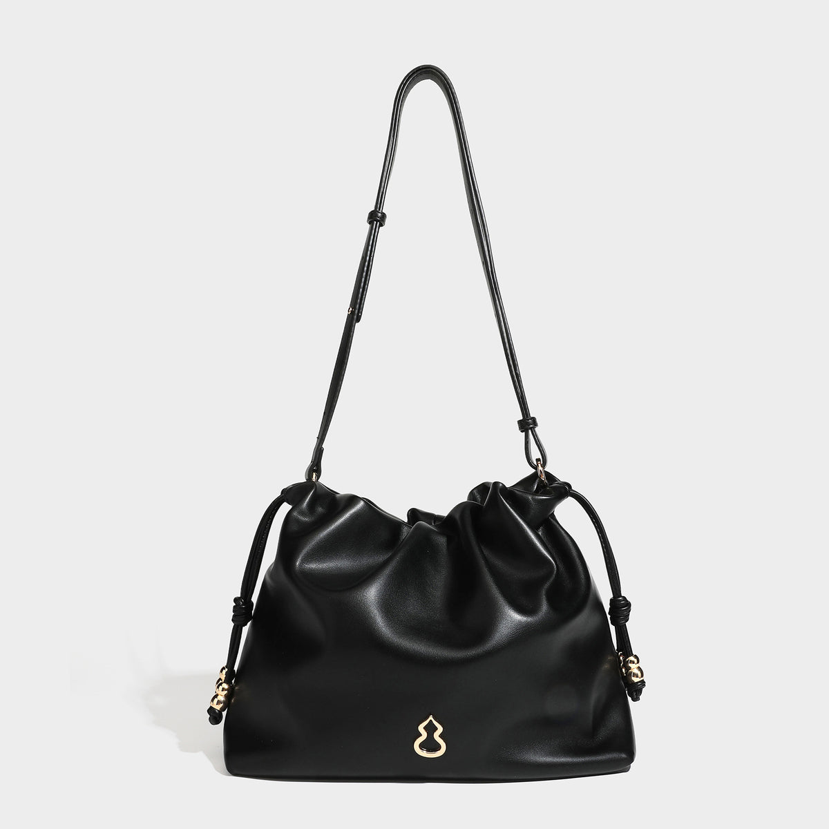 Slouchy ruched drawstring shoulder bag in smooth leather-look finish with gold-tone emblem and slim adjustable strap, detail