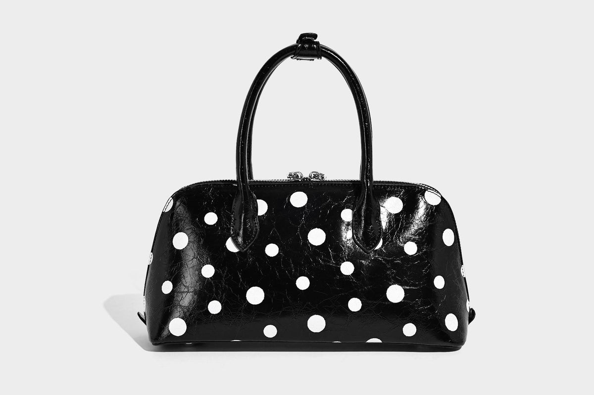 Glossy structured polka-dot satchel bag with dual top handles, silver turn-lock hardware, and detachable shoulder strap