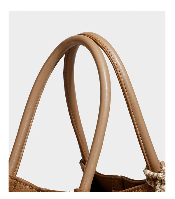 Pebbled leather-look bucket tote bag with rolled double handles, drawstring closure, braided cord charm, and detachable