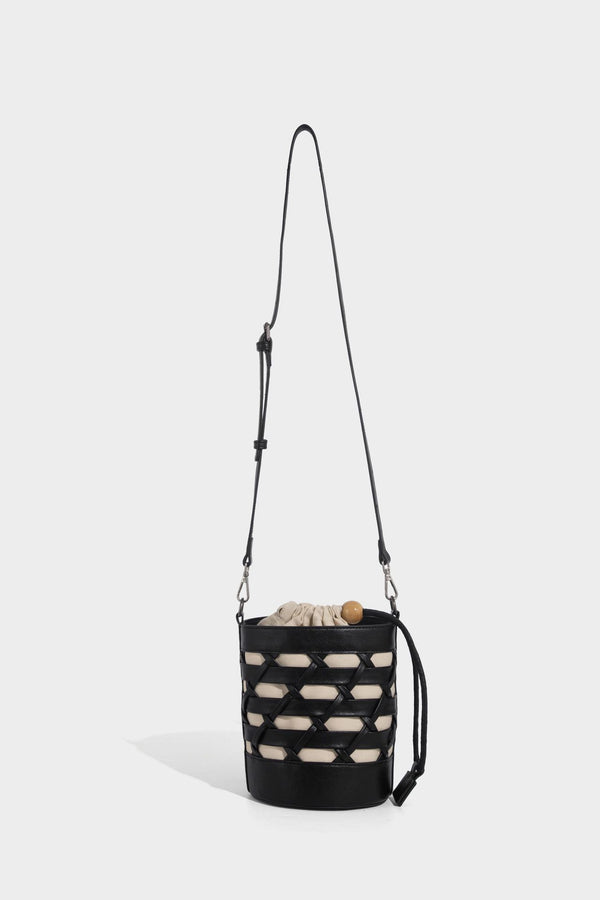 Small cylindrical woven lattice bucket bag with leather-look black trim, beige canvas body, wooden bead drawstring closure