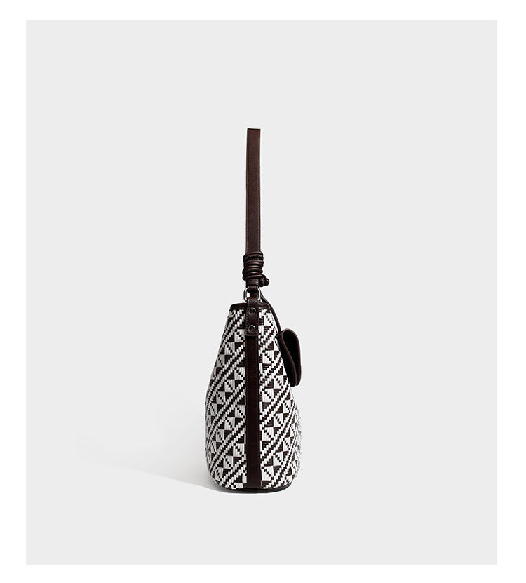Geflochtene Schultertasche mit geometrischem Ethno-Muster, Besatz in dunkelbrauner Lederoptik, langem verstellbarem Träger und kleinem hängendem Reißverschluss