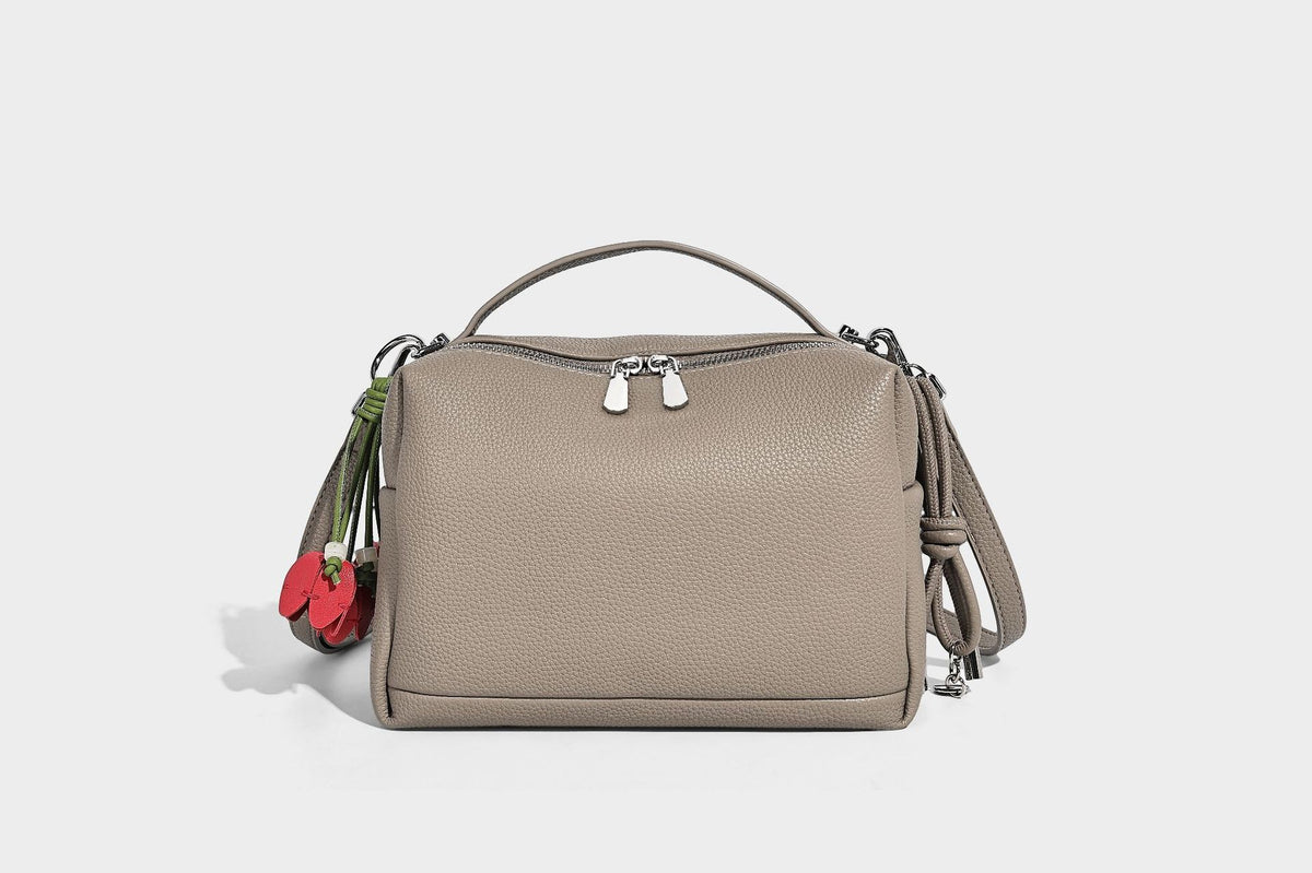 Kleine strukturierte Crossbody-Tasche mit Tragegriff aus genarbtem Material, Reißverschluss, silberfarbenen Beschlägen und optionalem Quastenanhänger