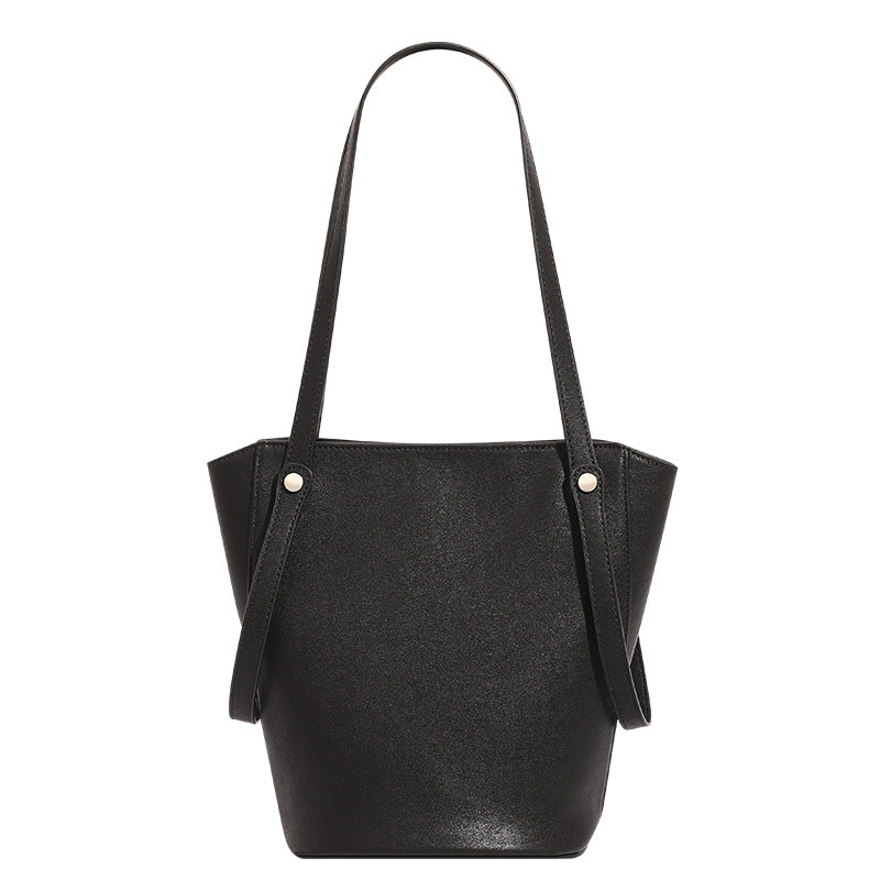 Structured black leather-look bucket tote bag with slim shoulder straps, silver-tone stud hardware, and tapered body, detail