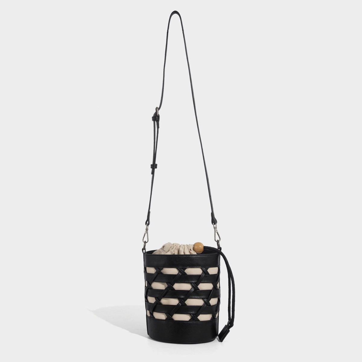 Small cylindrical woven lattice bucket bag with leather-look black trim, beige canvas body, wooden bead drawstring closure