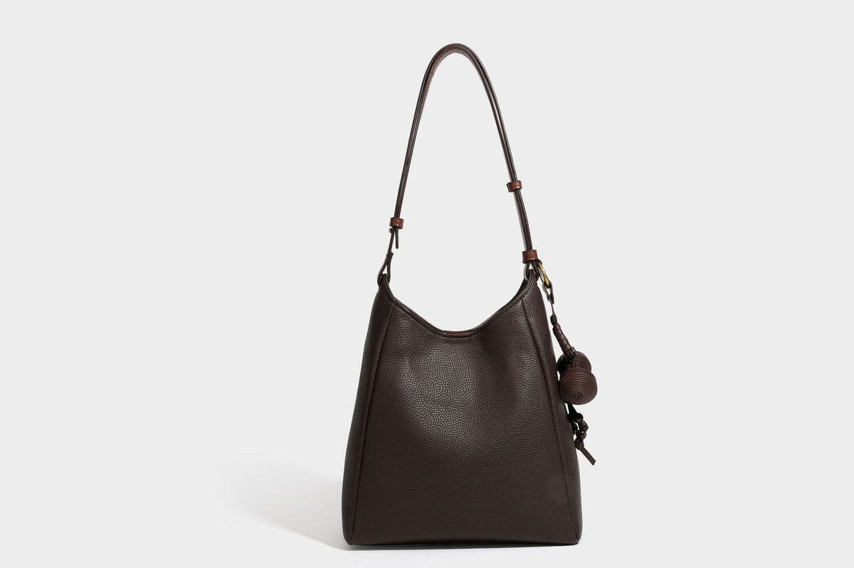Hobo-Schultertasche in dunklem Espresso mit genarbter Oberfläche, warmen cognacfarbenen Details, verstellbarem schmalem Riemen, goldfarbenen Ringbeschlägen und geknotetem