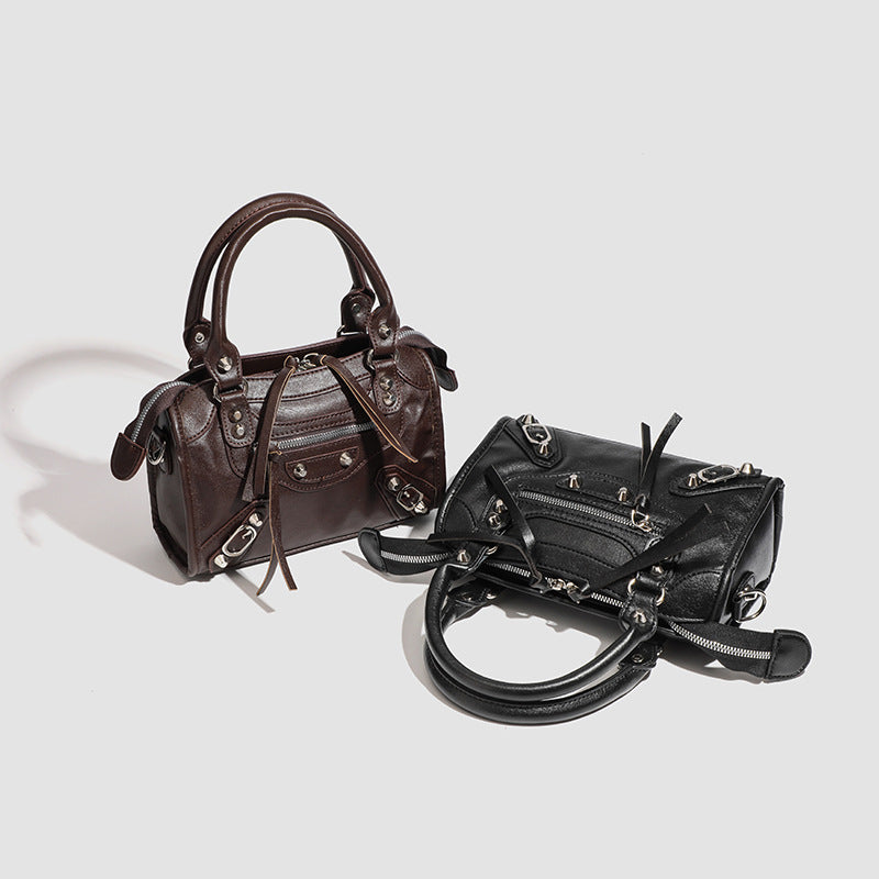 Mini-Henkeltasche mit formstabiler Silhouette, silberfarbenen Nietenbeschlägen, Reißverschlussfach vorne, zwei Tragegriffen und abnehmbarem Schulterriemen