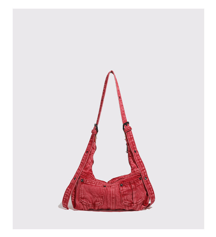Compact washed red distressed-textile shoulder bag with front flap pockets, dark metal hardware, and long adjustable strap