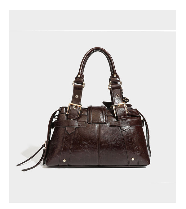Structured leather-look satchel bag with heart padlock charm, star charm, gold-tone buckle hardware, dual top handles, and