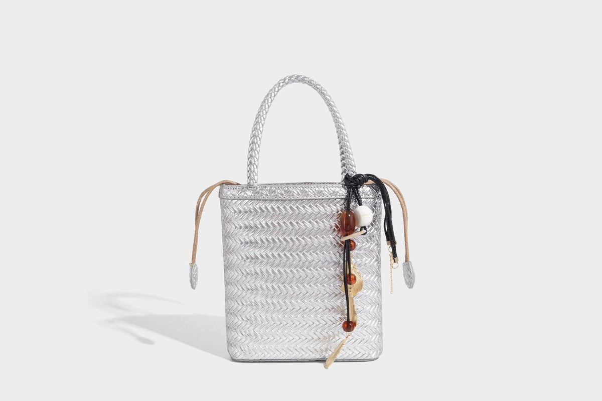 Small structured woven-texture tote bag with braided top handles and drawstring inner pouch, detail view 23