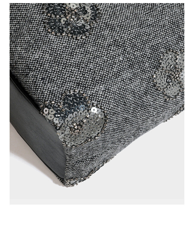 Lässig fallende, trapezförmige Schulter-Tote in Anthrazitgrau mit floralen Paillettenmotiven in Silber, Riemen in Lederoptik und herabhängendem Perlenbesatz