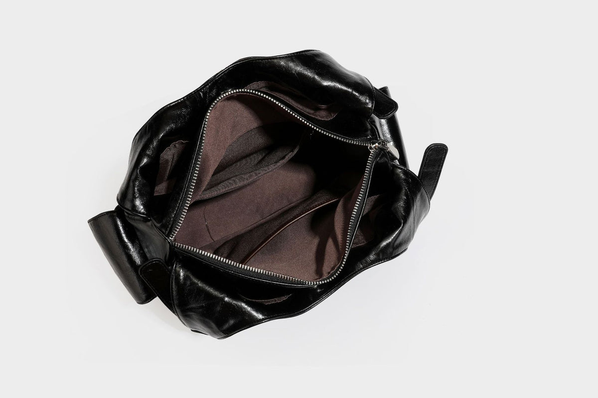 Große glänzende schwarze Hobo-Schultertasche mit silberfarbenem Ösen-Gürtelboden, Schnallenbeschlägen, vorderer Reißverschlusstasche und zwei …; Detailansicht