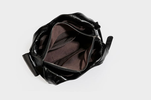 Große glänzende schwarze Hobo-Schultertasche mit silberfarbenem Ösen-Gürtelboden, Schnallenbeschlägen, vorderer Reißverschlusstasche und zwei …; Detailansicht