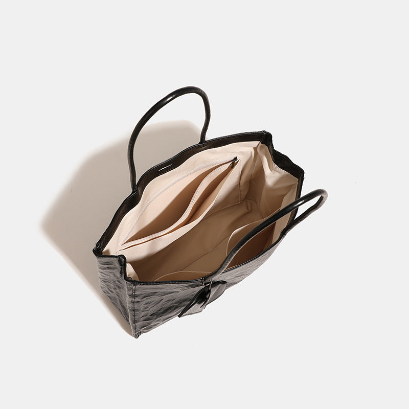 Large glossy crinkled rectangular tote bag with long double handles and hanging envelope snap tag, detail view 4