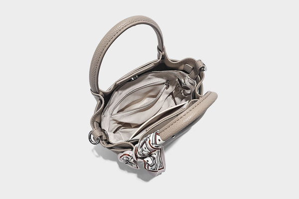 Kleine strukturierte Henkeltasche mit genarbter Oberfläche in Taupe, zwei Tragegriffen, bedrucktem Schalband, Drehverschluss an der Vorderseite und, Detail