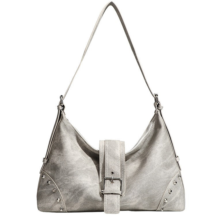 Slouchy trapezoid hobo shoulder bag with distressed textured finish, silver rivet corner accents, centre buckle strap, and