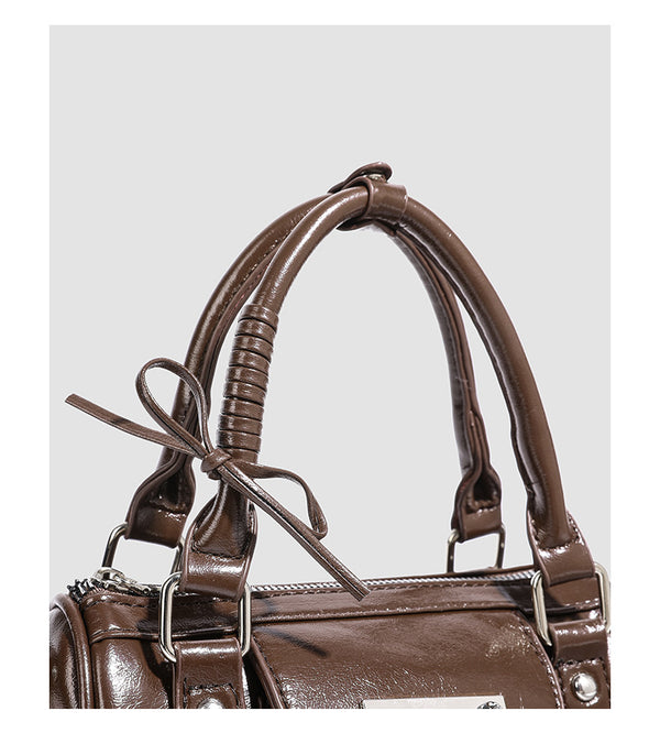 Kleine strukturierte Henkeltasche in glänzender Lederoptik mit Schleifen verzierten Henkeln und Vordertasche mit Herzverschluss, Detail