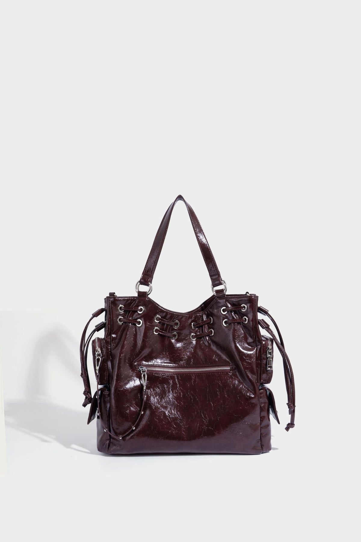 Glossy crinkled leather-look tote bag with silver grommet lace-up front detail, dual top handles, and detachable shoulder