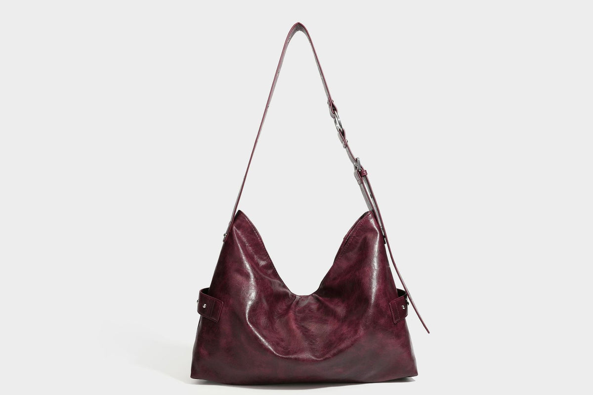 Lässig fallende Hobo-Schultertasche in glänzender Lederoptik mit Nieten in Silberoptik, Riemendetail mit Schnalle und Reißverschluss oben