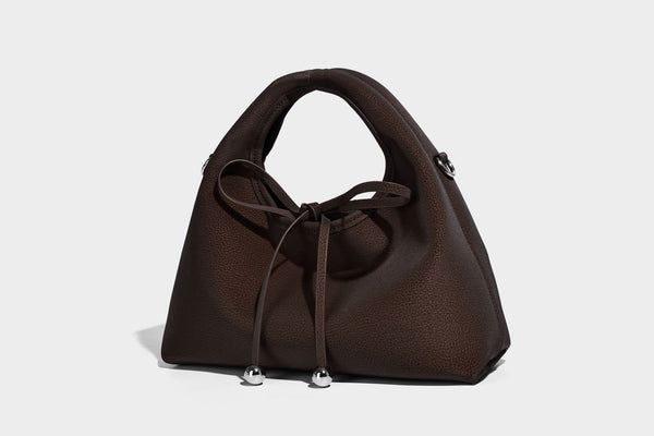 Pebbled matte trapezoid top-handle bag with drawstring bow closure, bead-tipped cords, silver-tone hardware, and detachable