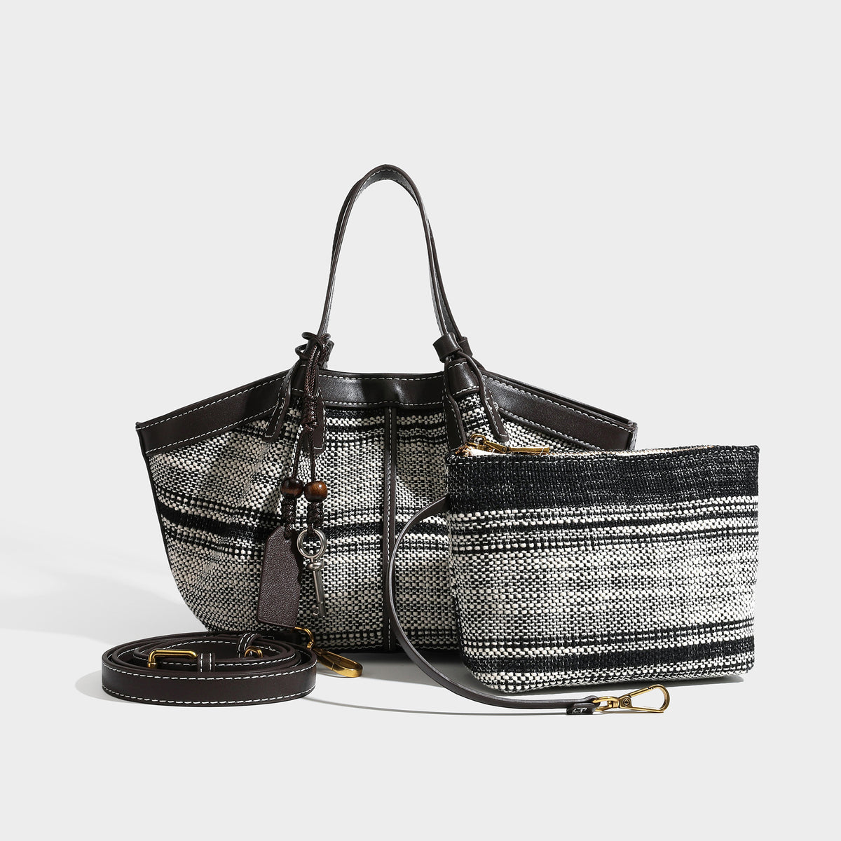 Black and white woven trapezoid tote bag with dark leather-look trim, white contrast stitching, double top handles, detail