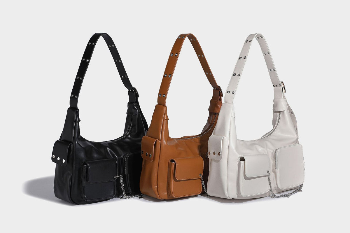 Lässig fallende Hobo-Schultertasche mit glänzender Lederoptik, vorderen Klappentaschen, Kettenapplikationen und silberfarbenen Nietbeschlägen