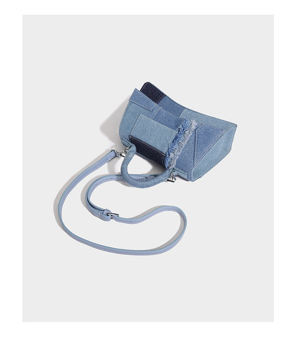 Structured patchwork denim trapezoid satchel bag with frayed panel trim, rounded top handle, and silver-tone hardware, detail