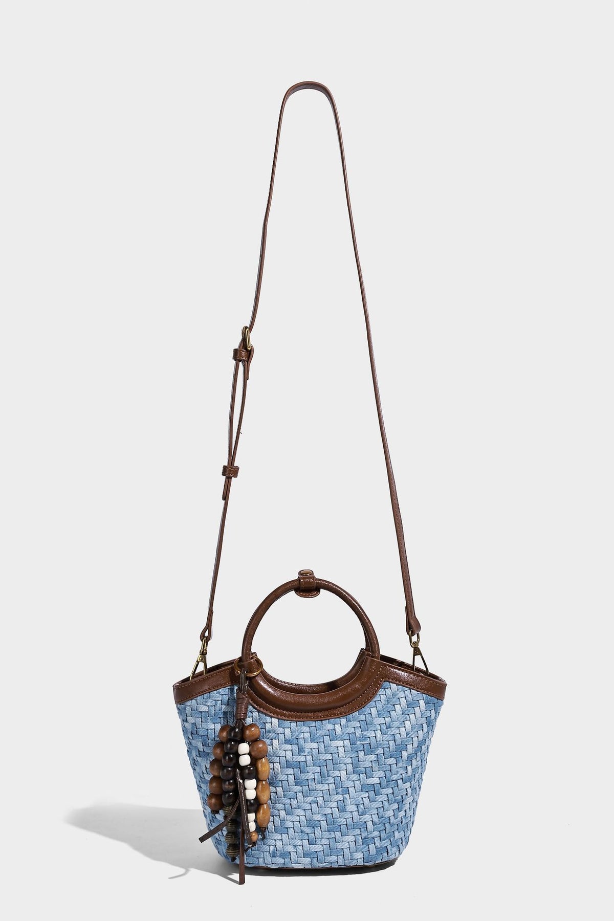 Blaue gewebte Bucket-Bag in Denim-Optik mit Besatz in brauner Lederoptik, rundem Henkel, Quastenanhänger mit Holzperlen und verstellbarem