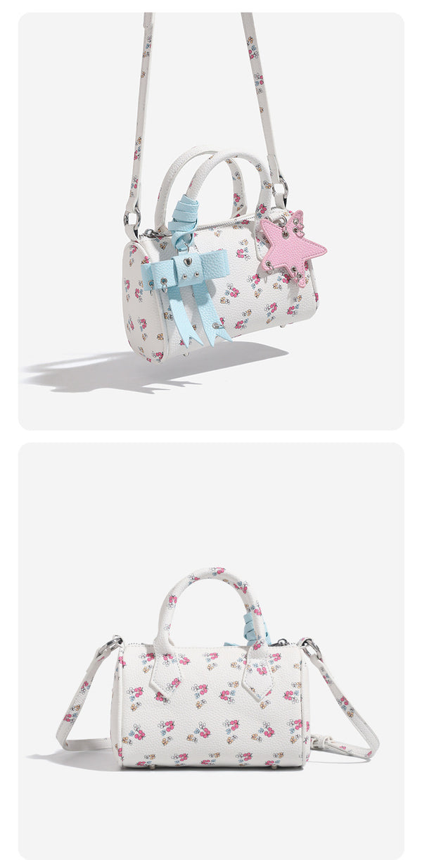 Mini-Boston-Tasche in Weiß mit genarbter Oberfläche, Blumen- oder Kirschprint, pastellblauem Schleifenanhänger, rosafarbenem Sternanhänger und zwei oberen