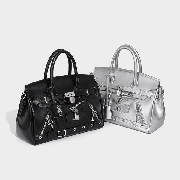 Structured black leather-look satchel bag with silver padlock hardware, front zip pockets, key charms, and top handles