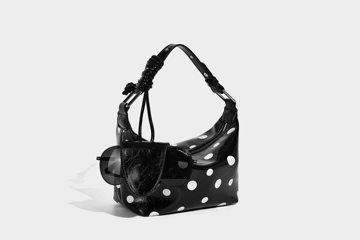Kompakte glänzende Hobo-Schultertasche in Schwarz mit weißen Punkten, Reißverschluss, Beschlägen in Gunmetal und befestigtem Überschlag vorne