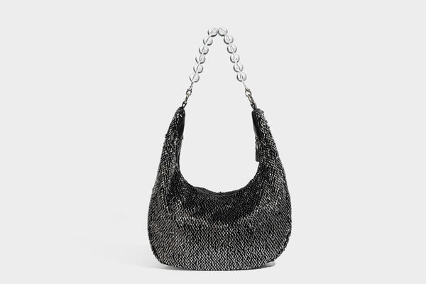 Kleine sichelförmige Schultertasche mit vollständig mit silberfarbenen Pailletten besetzter Außenseite, transparentem Henkel aus kugelförmigen Perlen und Reißverschluss in Silberoptik