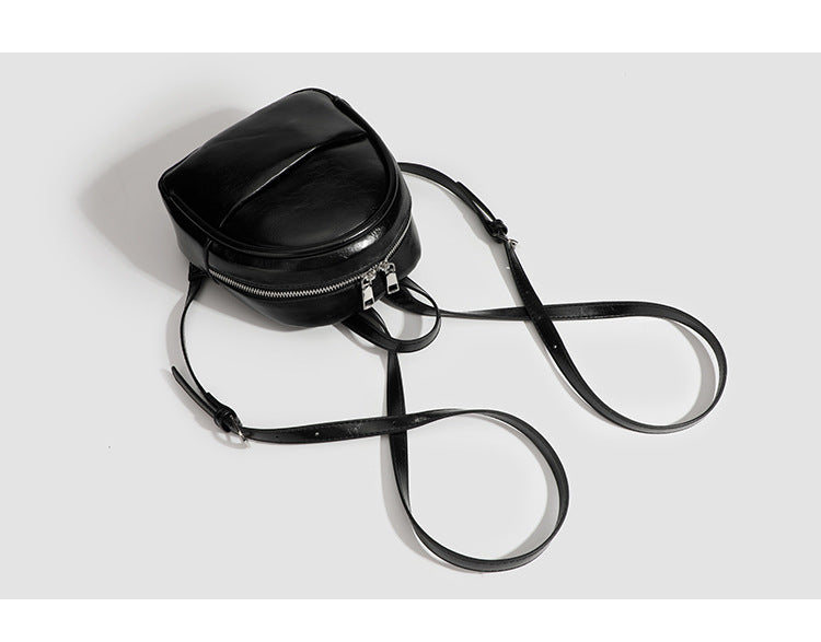 Kompakte, abgerundete Mini-Rucksacktasche mit glänzender Oberfläche in Lederoptik, Reißverschluss oben, Fronttasche, Tragegriff oben und, Detail