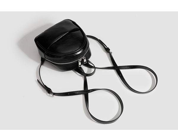 Kompakte, abgerundete Mini-Rucksacktasche mit glänzender Oberfläche in Lederoptik, Reißverschluss oben, Fronttasche, Tragegriff oben und, Detail
