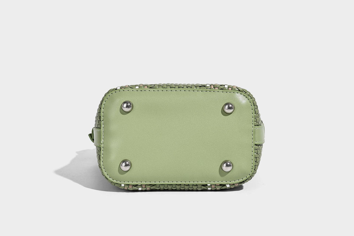 Small woven bucket bag with drawstring top, braided handle, detachable crossbody strap, and silver-tone ring hardware, detail