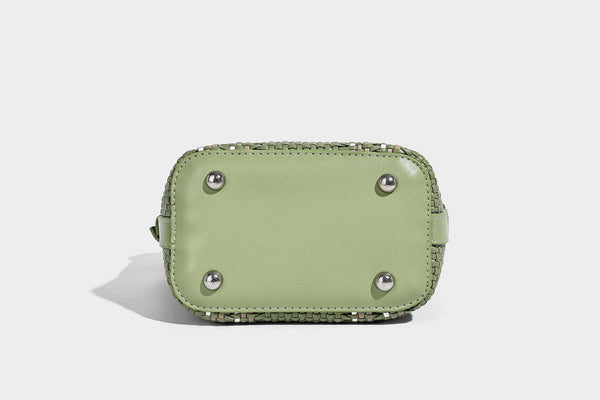 Small woven bucket bag with drawstring top, braided handle, detachable crossbody strap, and silver-tone ring hardware, detail