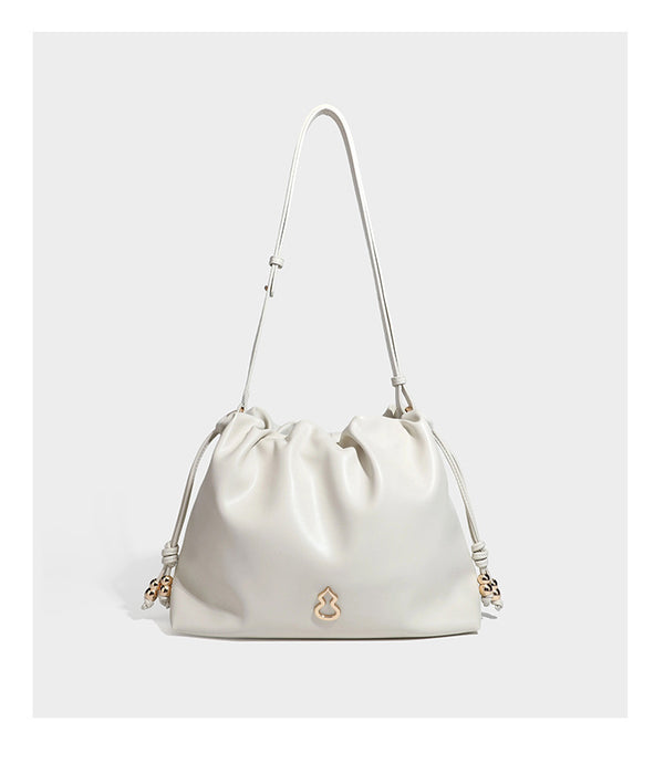 Slouchy ruched drawstring shoulder bag in smooth leather-look finish with gold-tone emblem and slim adjustable strap, detail