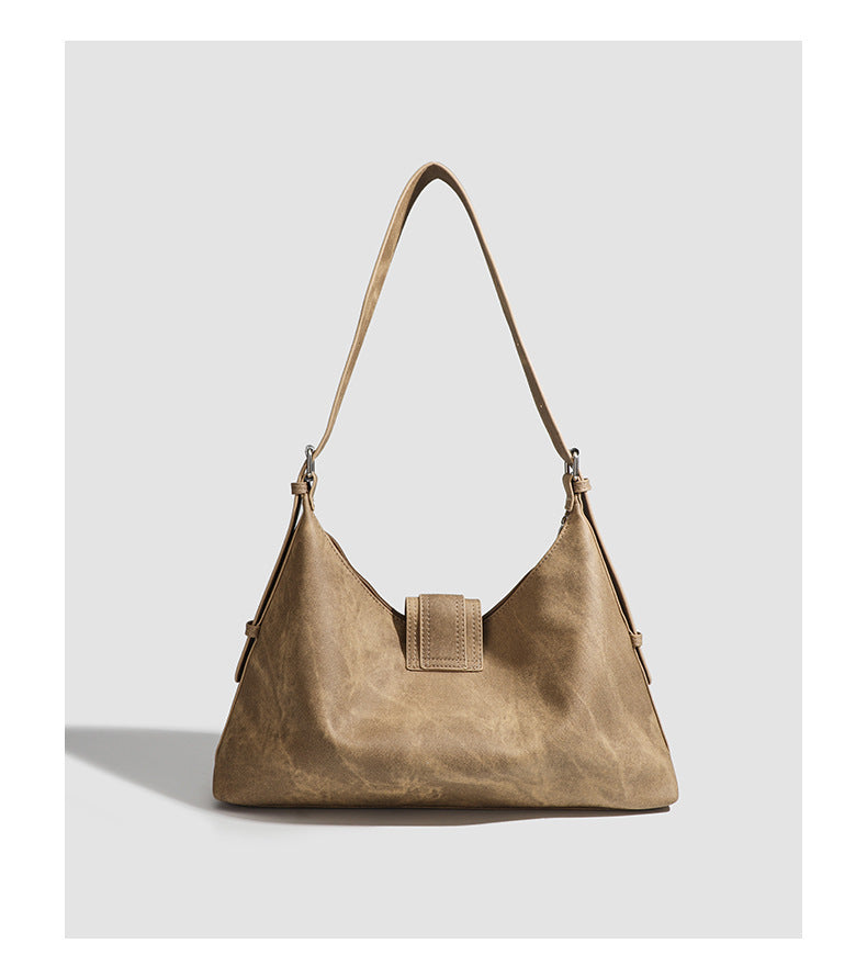 Slouchy trapezoid hobo shoulder bag with distressed textured finish, silver rivet corner accents, centre buckle strap, and