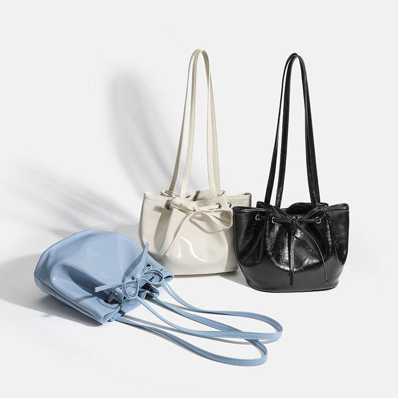 Soft glossy leather-look bucket bag with bow drawstring closure and silver-tone grommets, detail view 2
