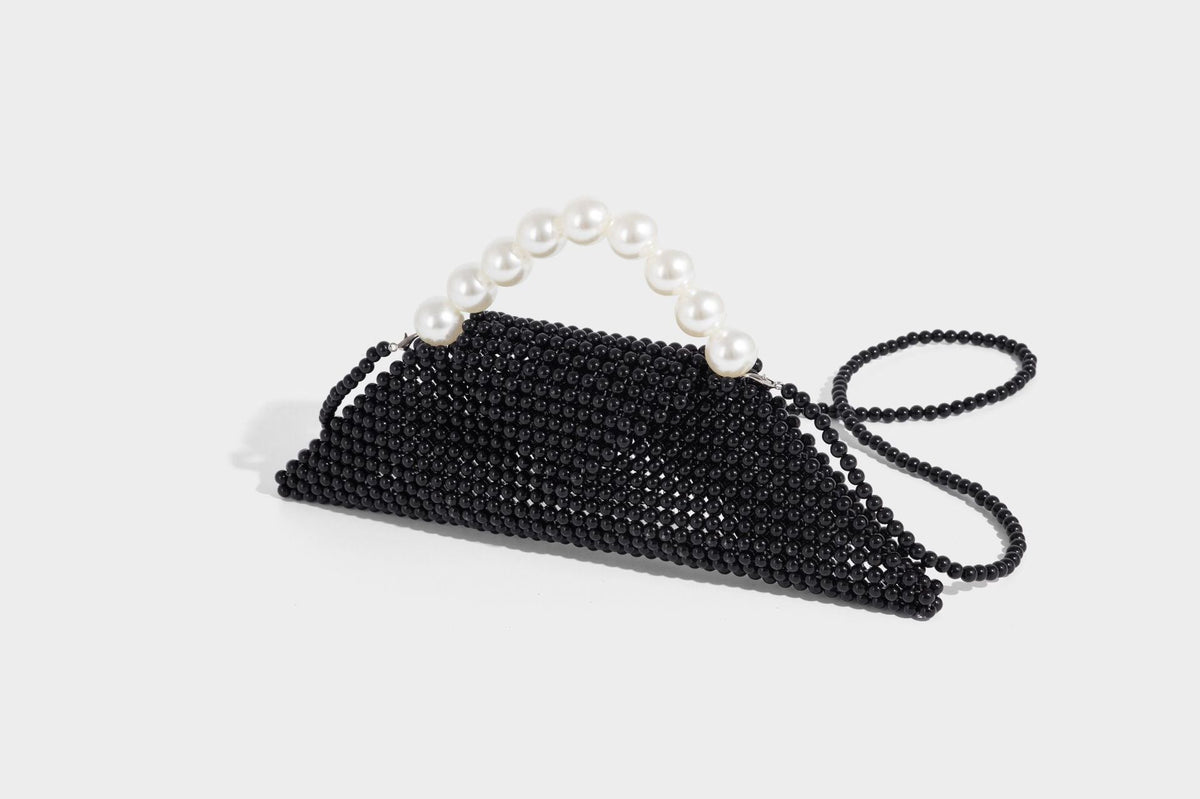 Small structured triangle clutch bag covered in glossy pearl beads with an arched pearl top handle and silver snap closure