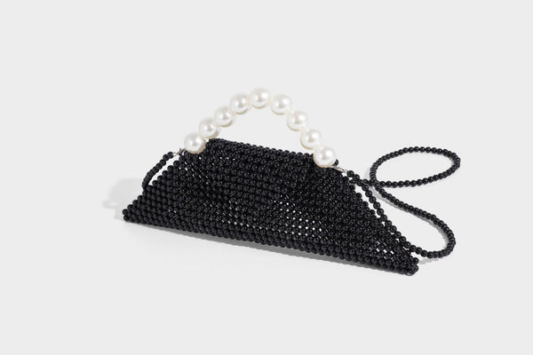Small structured triangle clutch bag covered in glossy pearl beads with an arched pearl top handle and silver snap closure