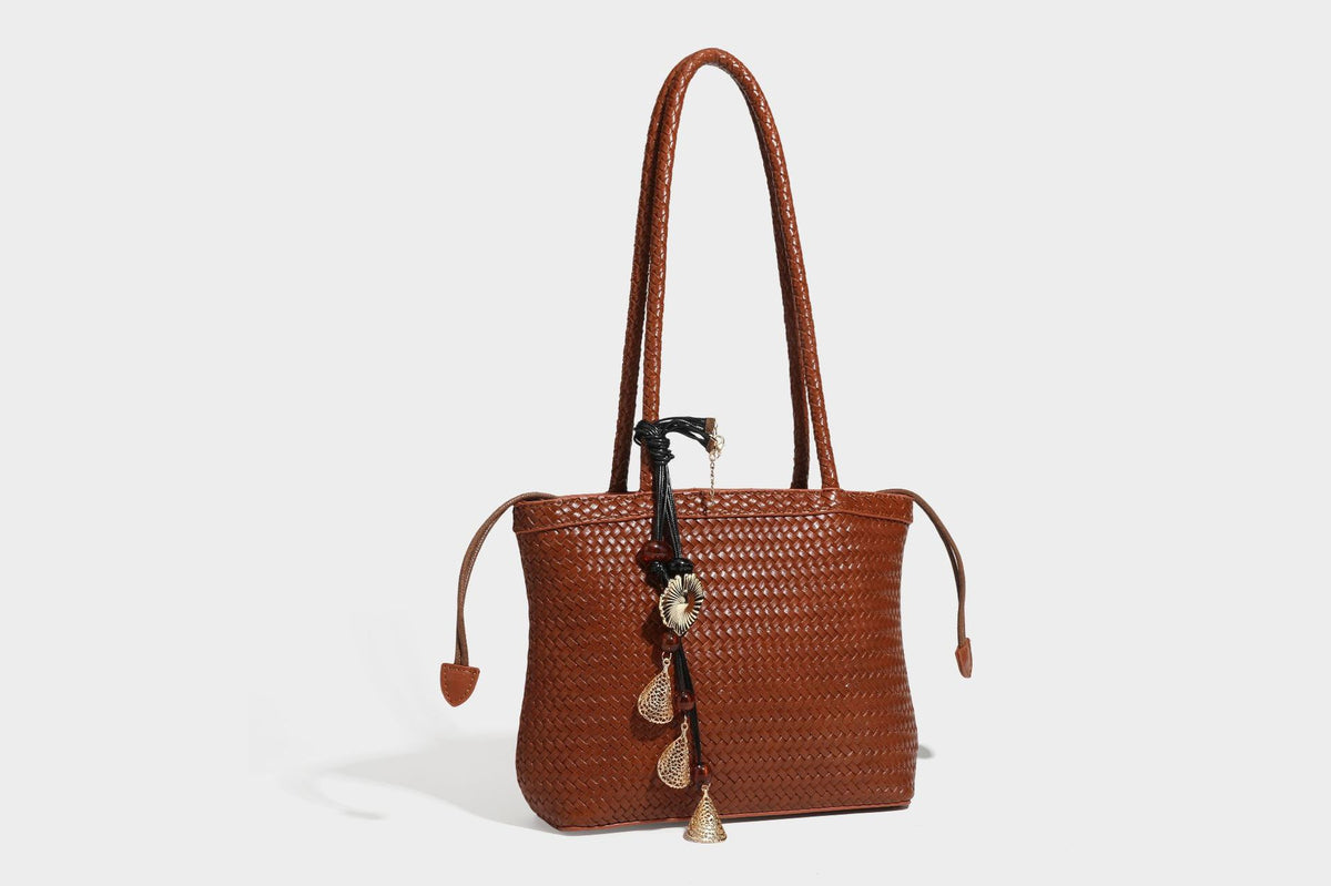 Structured woven leather-look tote bag in dark brown with long shoulder straps, side drawstring ties, and gold filigree