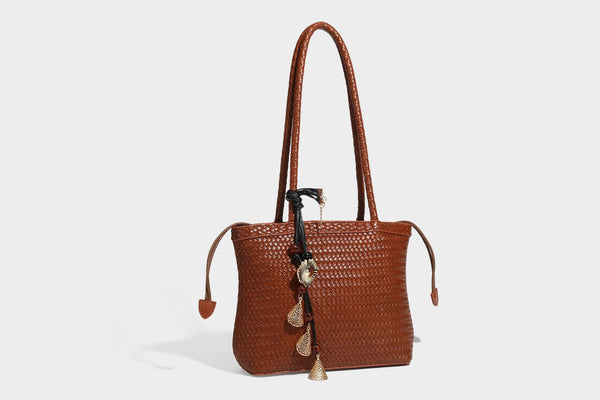 Structured woven leather-look tote bag in dark brown with long shoulder straps, side drawstring ties, and gold filigree