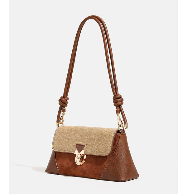 Structured trapezoid shoulder bag with pale textured flap, gold-tone triangular turn-lock closure, and long knotted cord