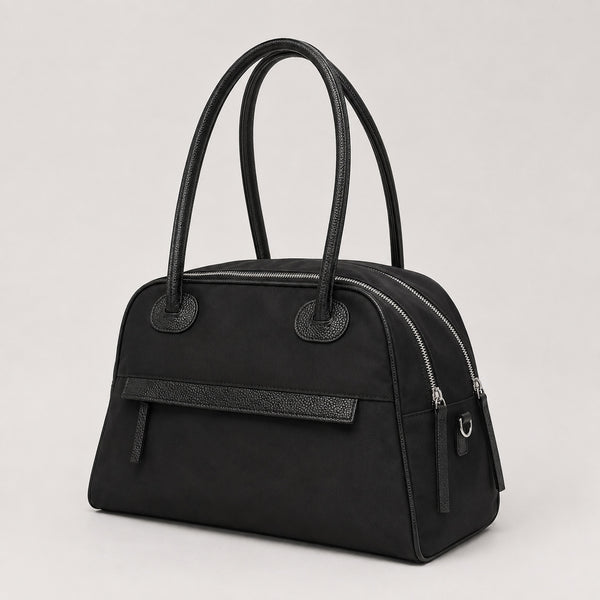 Structured dome top-handle bag in matte nylon with pebbled vegan leather-look trim, zip-top closure, front slip pocket, and