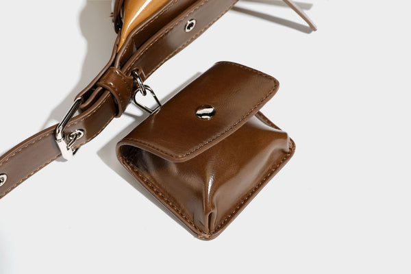 Glossy leather-look crescent hobo shoulder bag with dark contrast trim, silver-tone hardware, and attached mini flap pouch