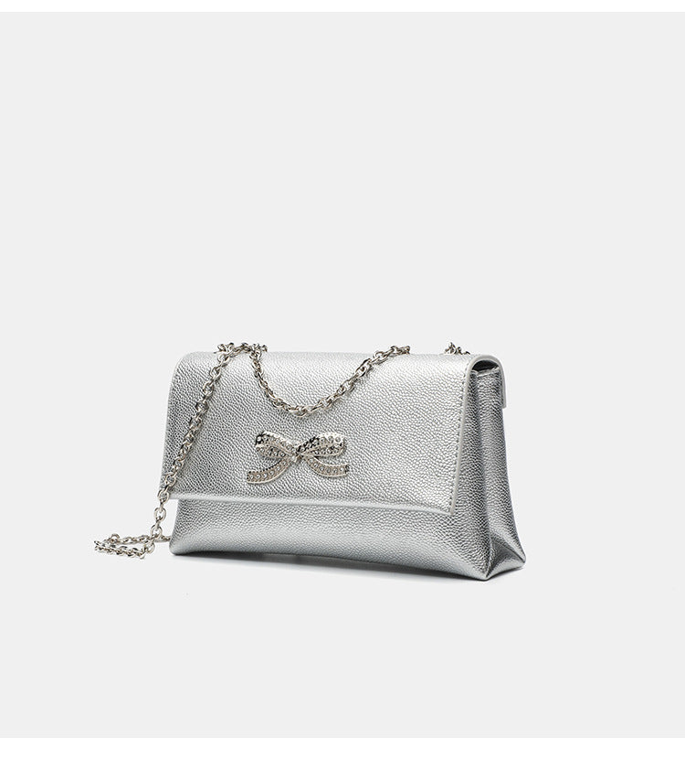 Structured rectangular flap crossbody bag with rhinestone bow and silver chain strap in pebbled finish, detail view 15