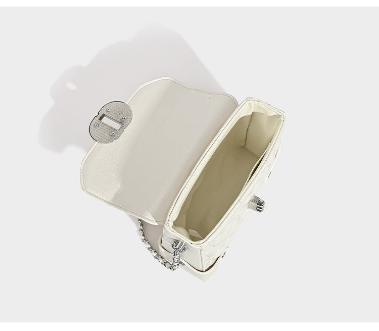 Kleine strukturierte Box-Tasche aus herzförmig gestepptem PU mit Henkel, silberfarbenem Kettenriemen zum Tragen als Crossbody und ovalem Drehverschluss, Detailansicht